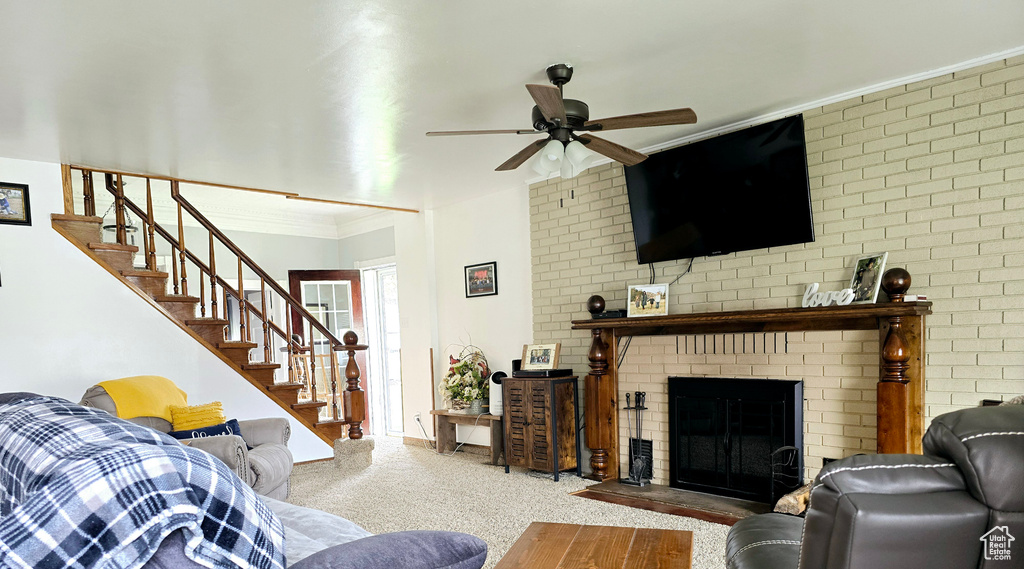 Living room with brick wall, crown molding, a brick fireplace, and ceiling fan