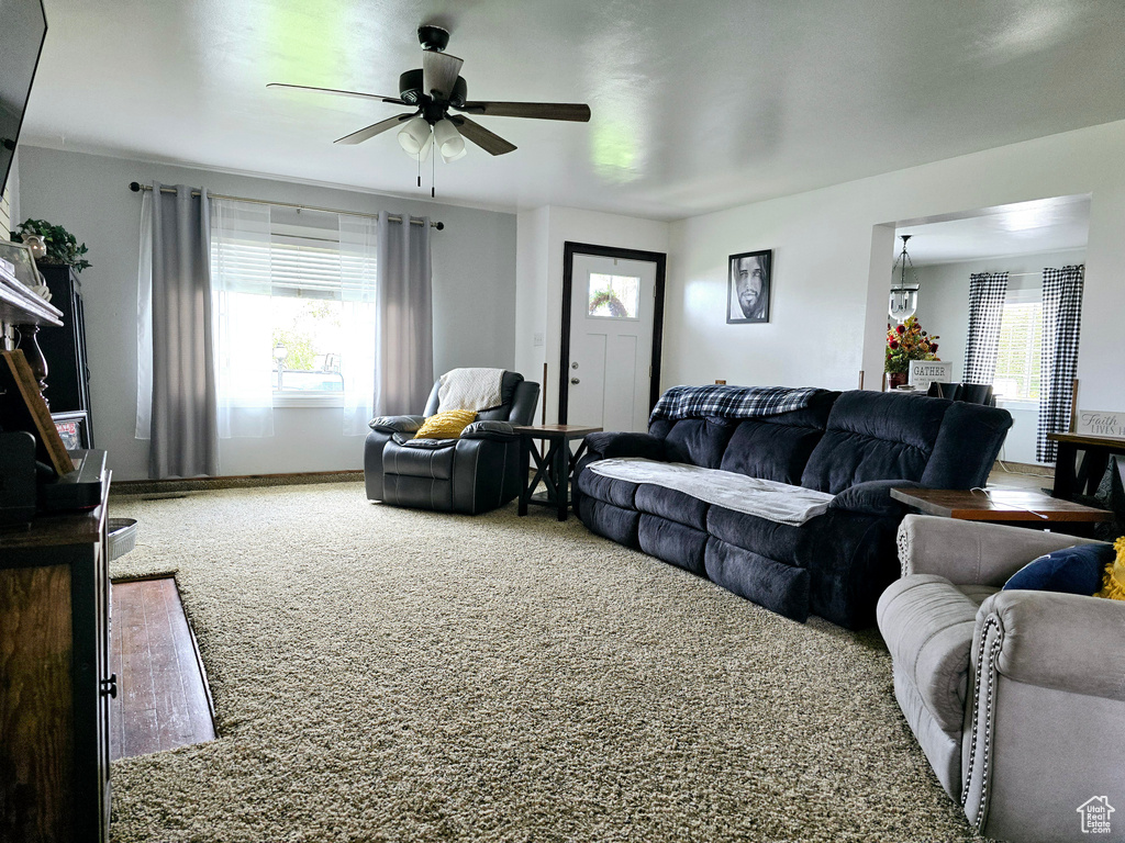 Carpeted living room with a healthy amount of sunlight and ceiling fan