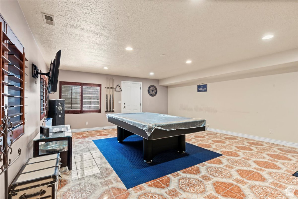 Recreation room with light tile flooring, a textured ceiling, and billiards