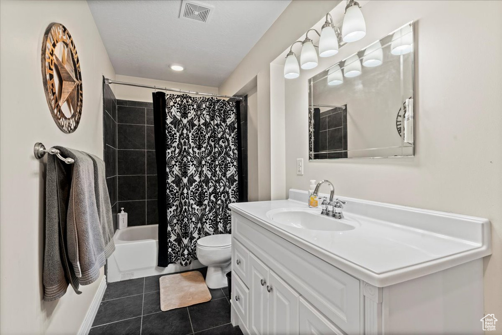 Full bathroom with tile floors, toilet, shower / bath combination with curtain, and large vanity