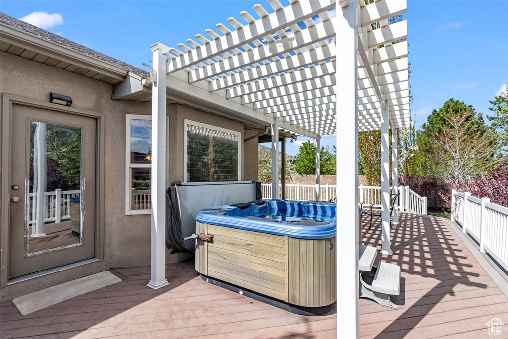 Wooden deck with a hot tub and a pergola