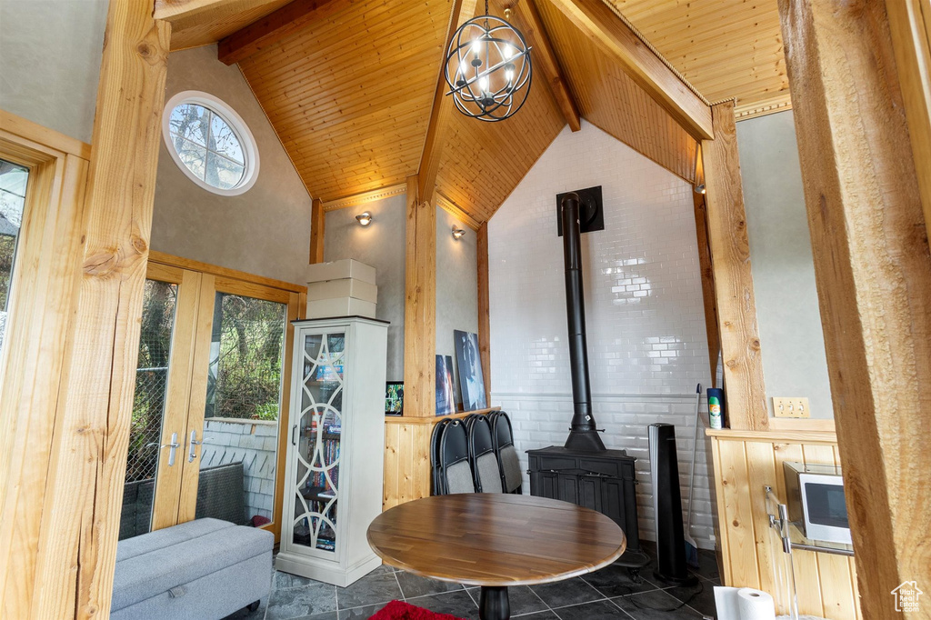 Interior space with a wood stove, high vaulted ceiling, an inviting chandelier, beam ceiling, and wood ceiling