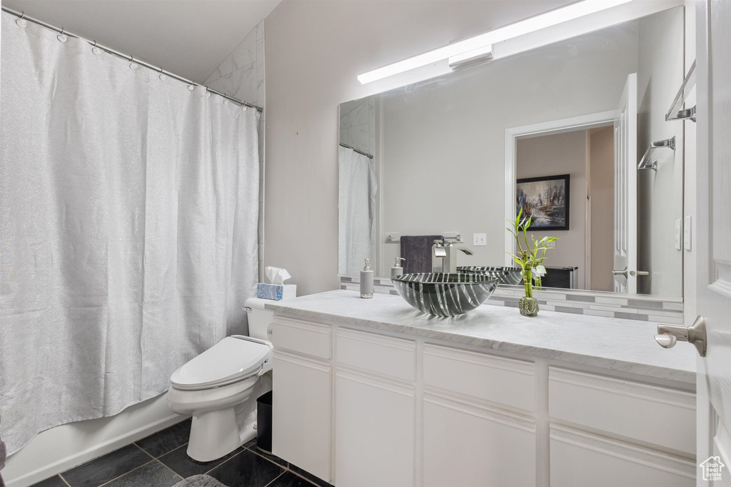 Full bathroom featuring tile flooring, vanity with extensive cabinet space, toilet, and shower / tub combo with curtain