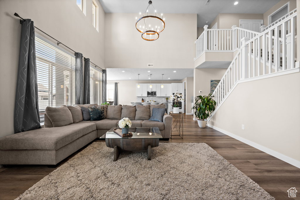 Living room featuring dark hardwood / wood-style flooring, a notable chandelier, and a high ceiling