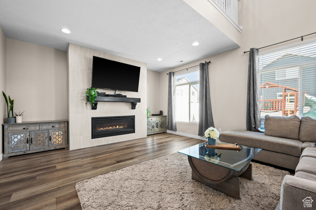 Living room with dark hardwood / wood-style flooring and a tiled fireplace
