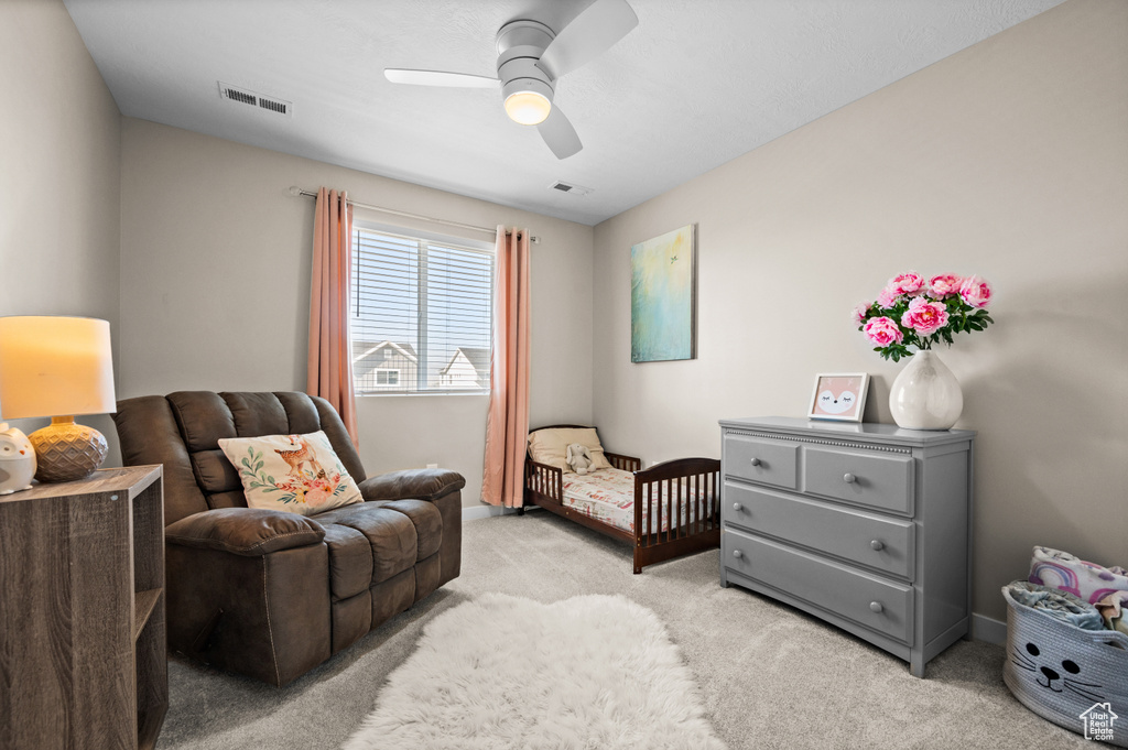 Carpeted bedroom with a nursery area and ceiling fan