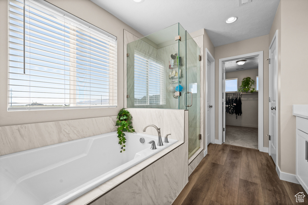 Bathroom with hardwood / wood-style floors, vanity, and shower with separate bathtub
