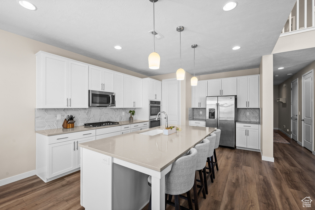 Kitchen featuring backsplash, appliances with stainless steel finishes, white cabinets, and dark hardwood / wood-style floors