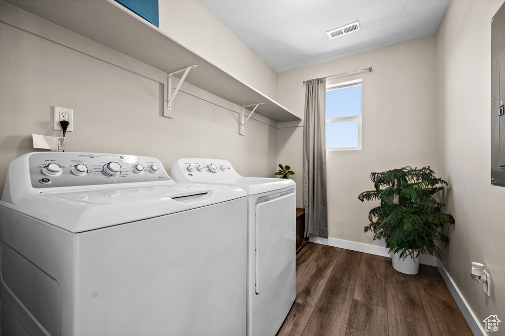 Clothes washing area with washing machine and dryer and dark wood-type flooring