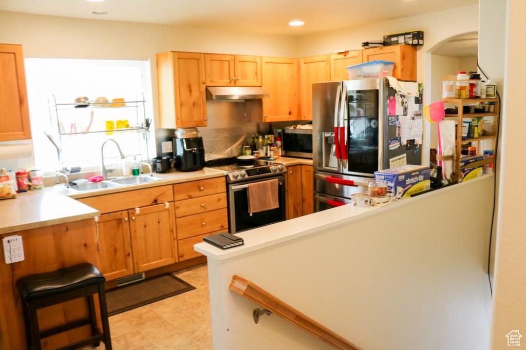 Kitchen featuring sink, stainless steel appliances, light tile floors, and tasteful backsplash