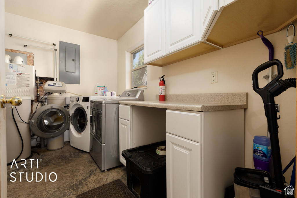 Laundry area featuring washer and clothes dryer, dark tile floors, water heater, and cabinets