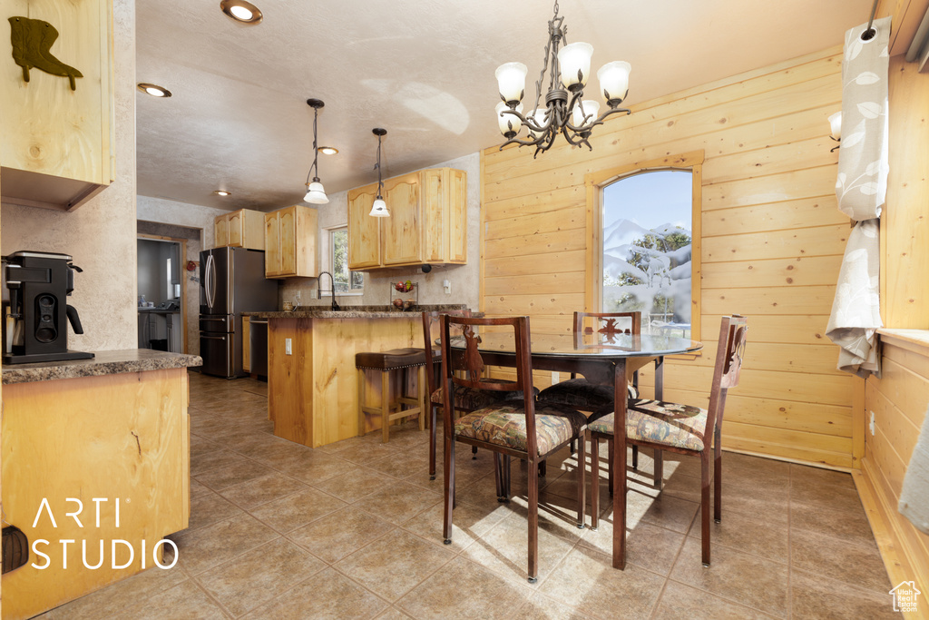 Tiled dining area with wood walls, a notable chandelier, and sink