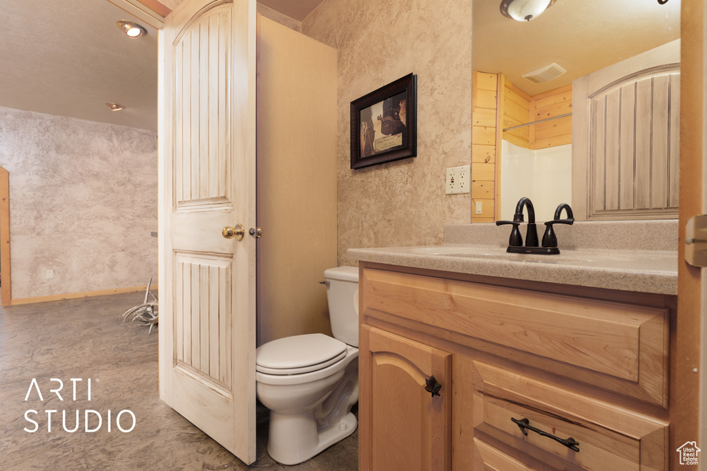 Bathroom with vanity with extensive cabinet space and toilet