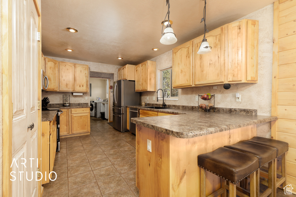 Kitchen featuring decorative light fixtures, separate washer and dryer, stainless steel appliances, light tile floors, and sink