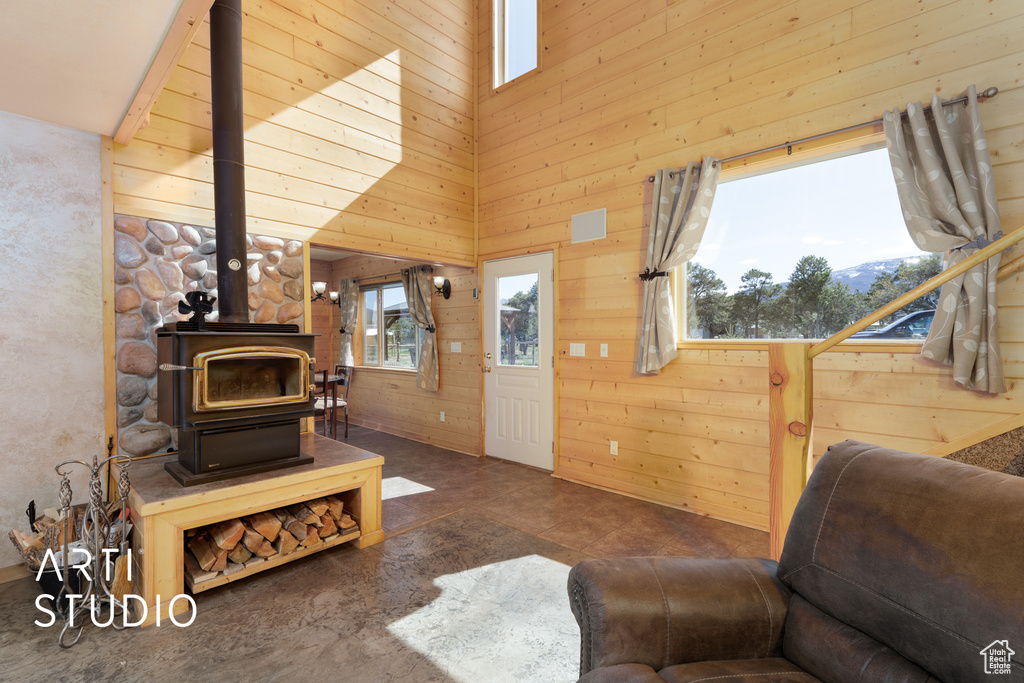 Tiled living room featuring a wood stove and wooden walls