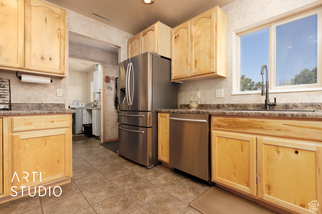 Kitchen with appliances with stainless steel finishes, light brown cabinets, sink, and tile flooring