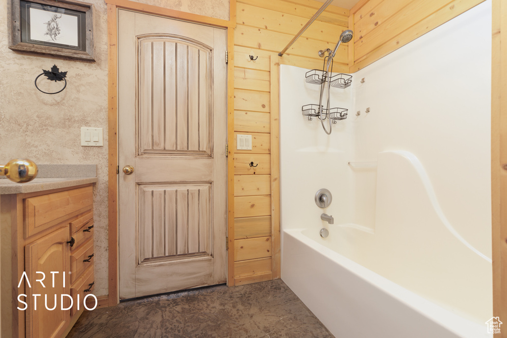 Bathroom with tile flooring, vaulted ceiling, vanity, and tub / shower combination