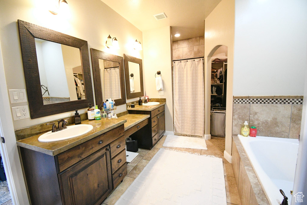 Bathroom with vanity, a relaxing tiled bath, and tile floors