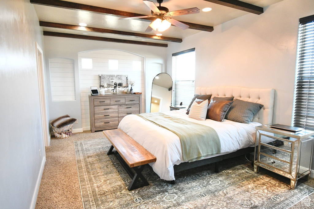 Carpeted bedroom with ceiling fan and beamed ceiling