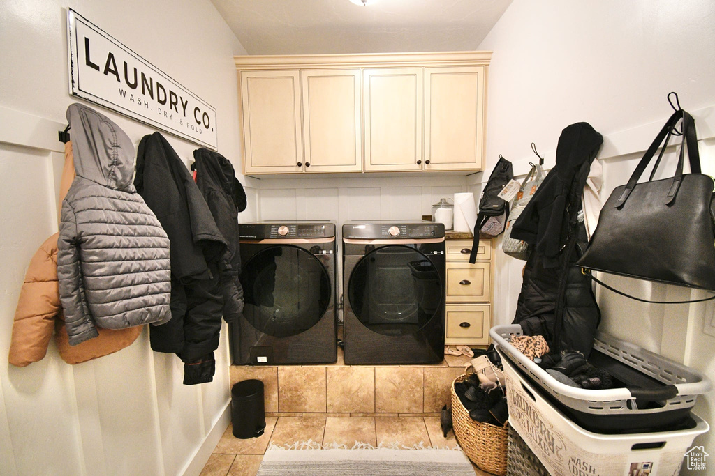 Laundry room featuring independent washer and dryer, cabinets, and light tile floors