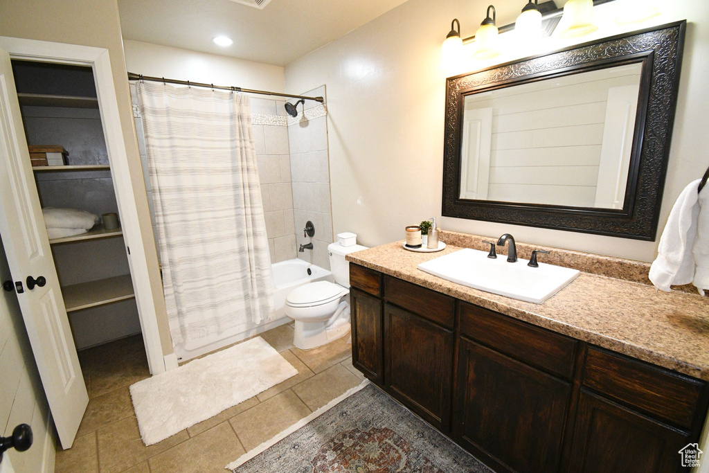 Full bathroom with shower / tub combo with curtain, vanity with extensive cabinet space, toilet, and tile flooring