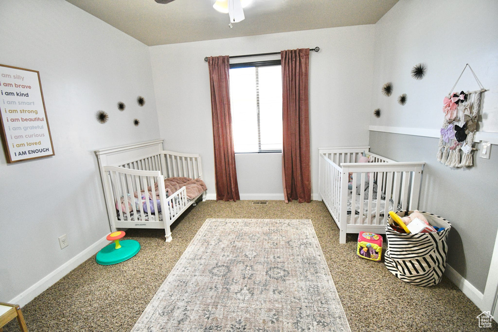 Carpeted bedroom with a nursery area and ceiling fan