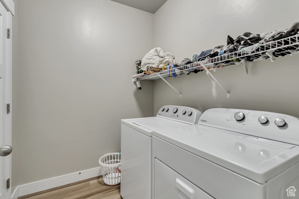 Laundry room featuring light wood-type flooring and washer and clothes dryer