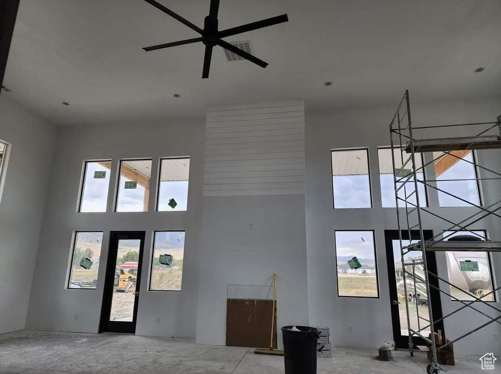 Entrance foyer featuring ceiling fan, concrete floors, and a high ceiling