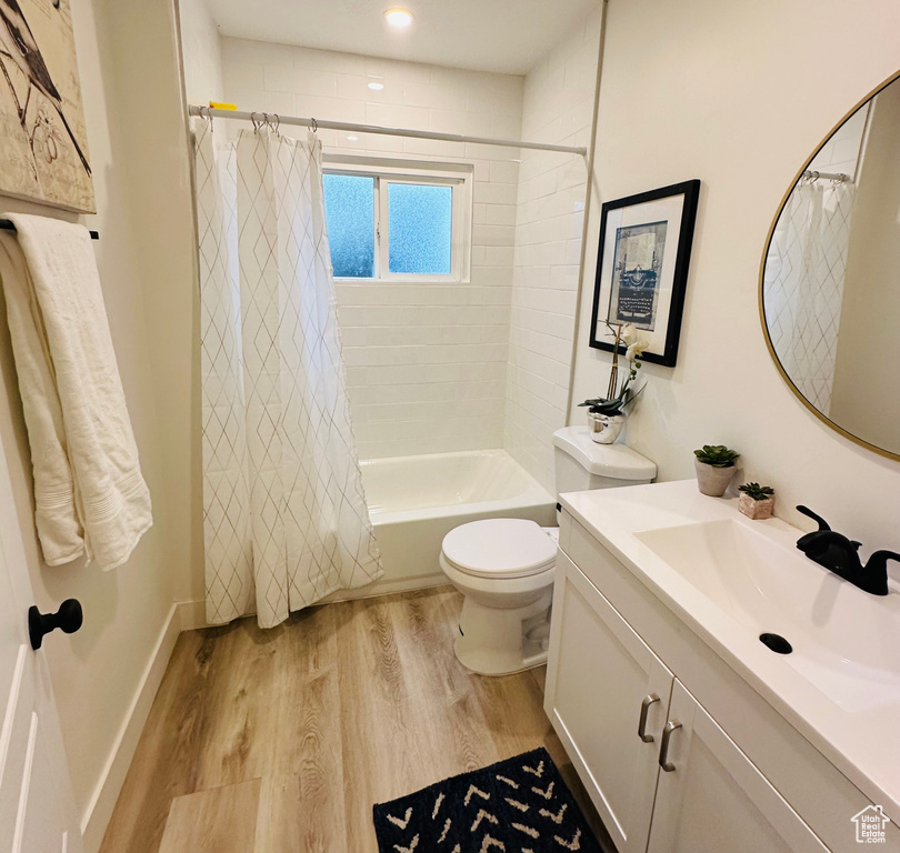 Full bathroom featuring shower / tub combo with curtain, hardwood / wood-style floors, vanity, and toilet