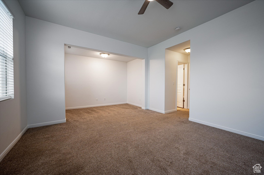 Unfurnished room featuring carpet flooring, ceiling fan, and plenty of natural light