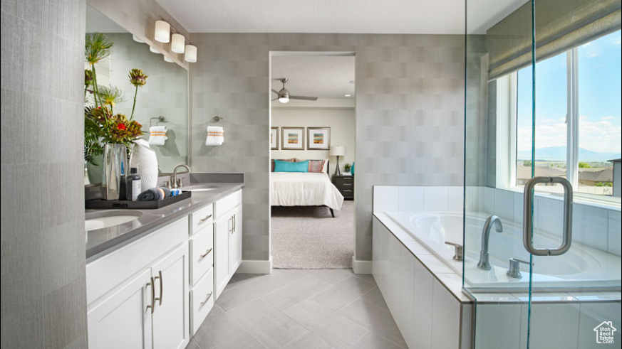 Bathroom featuring dual bowl vanity, tile walls, tile flooring, a relaxing tiled bath, and ceiling fan
