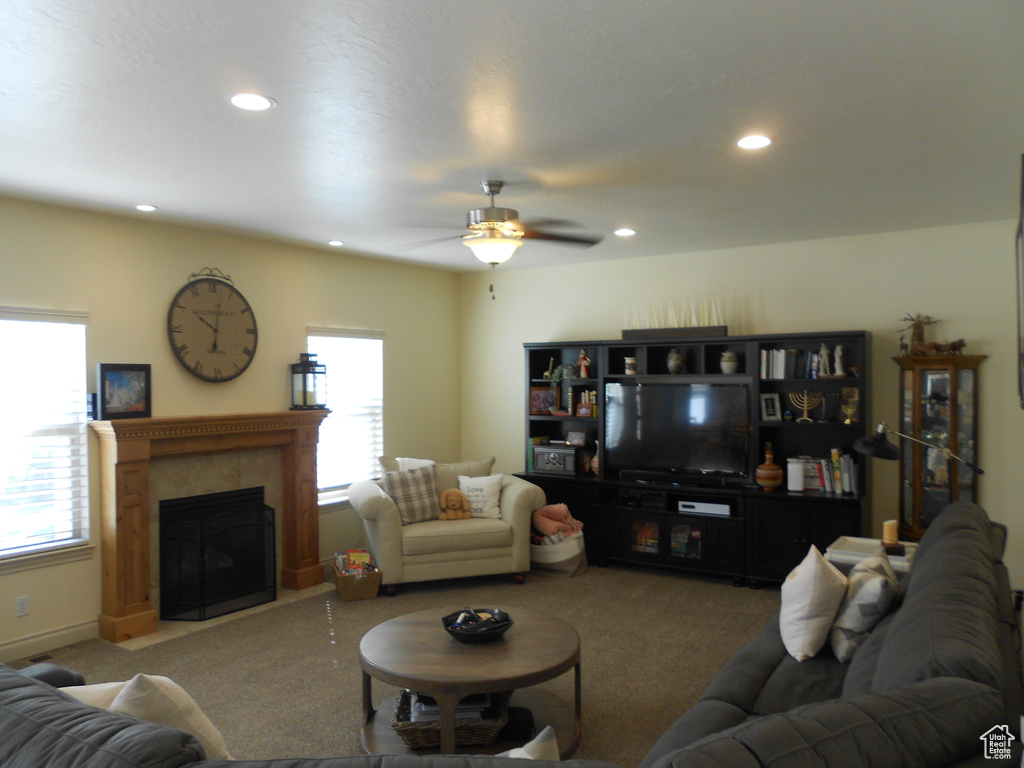 Living room featuring ceiling fan, a tile fireplace, and carpet floors