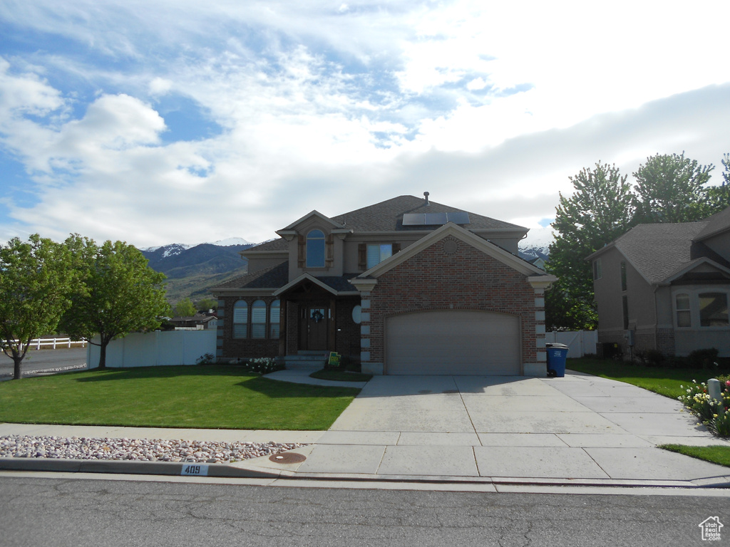 View of front of home featuring a front yard, a mountain view, and a garage