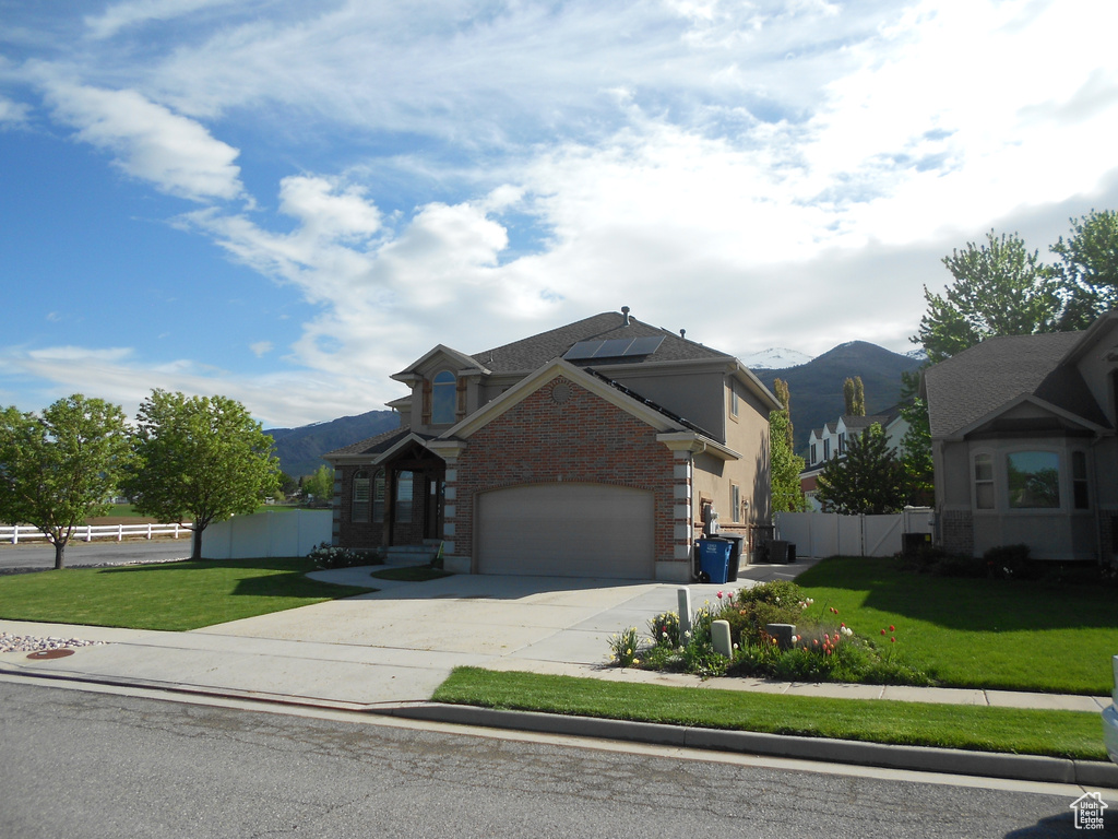 View of front of house with a mountain view, a garage, and a front lawn