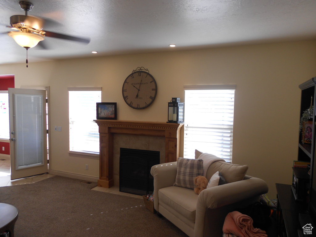 Living room with a tiled fireplace, ceiling fan, and carpet floors