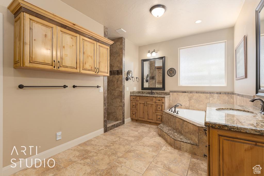 Bathroom with vanity with extensive cabinet space, shower with separate bathtub, and tile floors