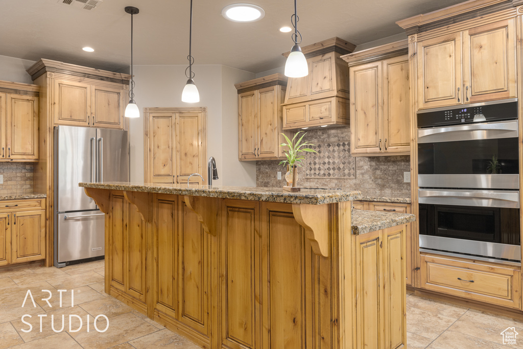 Kitchen featuring backsplash, appliances with stainless steel finishes, a kitchen island with sink, a kitchen breakfast bar, and light tile floors