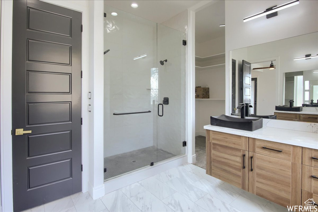 Bathroom featuring a shower with shower door, vanity, and tile floors