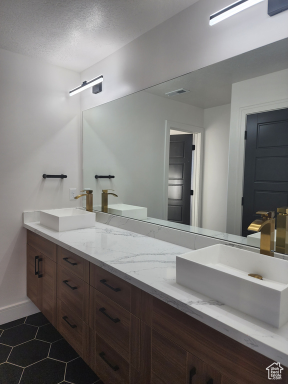 Bathroom with dual sinks, tile flooring, a textured ceiling, and large vanity