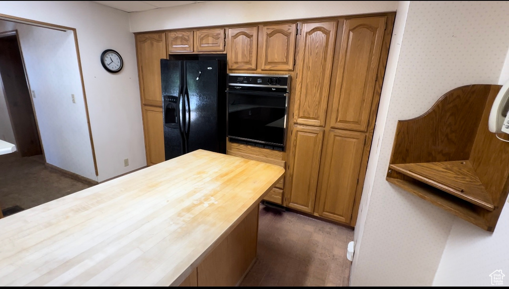 Kitchen with butcher block countertops, dark hardwood / wood-style flooring, and black appliances