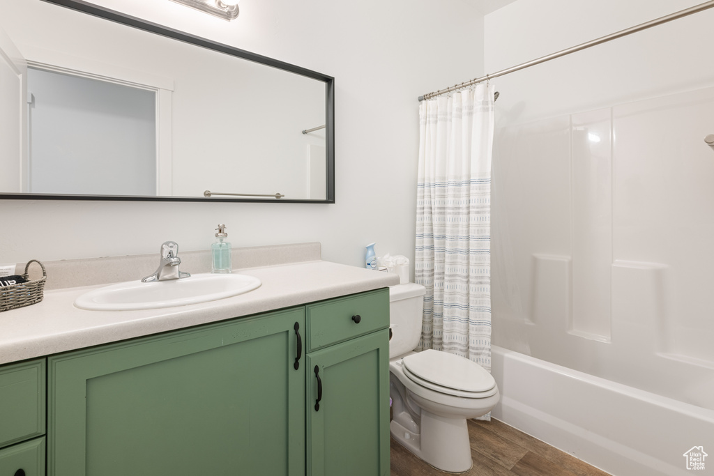 Full bathroom featuring wood-type flooring, shower / bath combo, vanity, and toilet