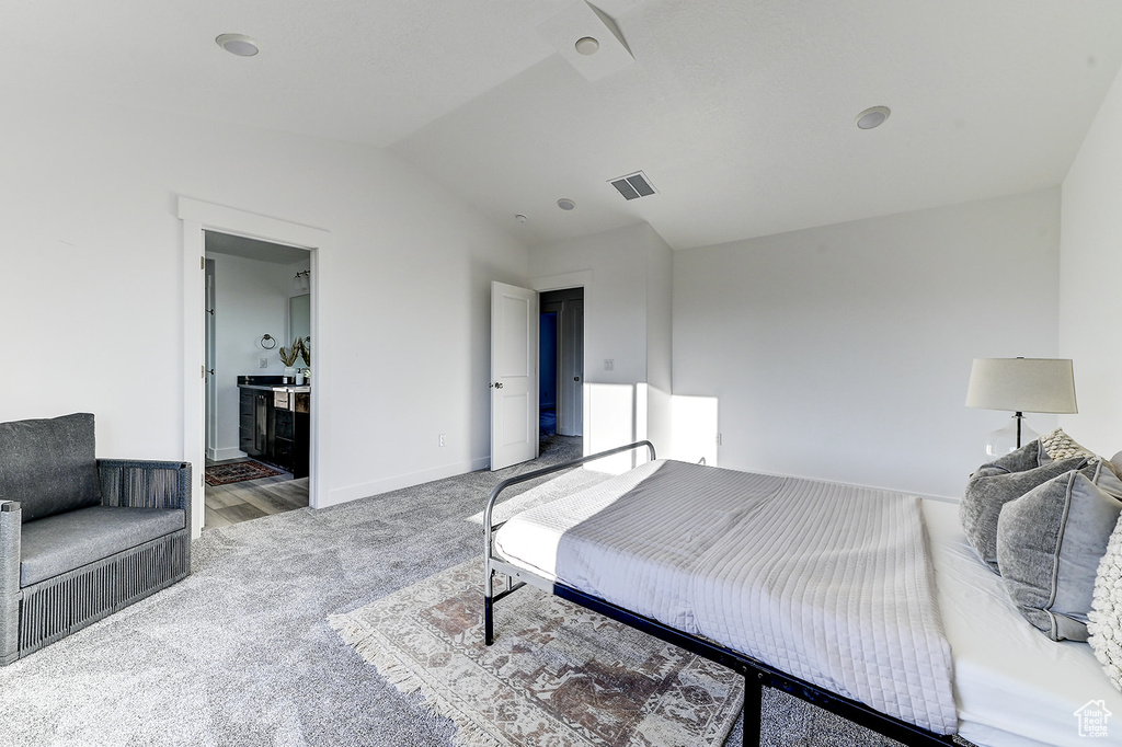 Carpeted bedroom featuring connected bathroom and vaulted ceiling