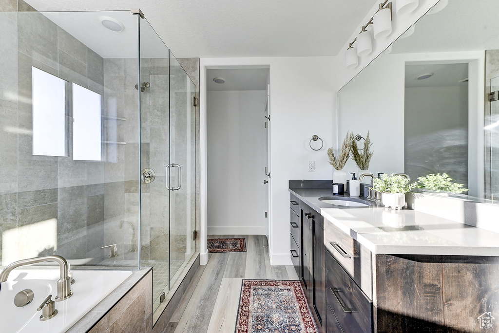 Bathroom with an enclosed shower, a wealth of natural light, double sink vanity, and hardwood / wood-style flooring