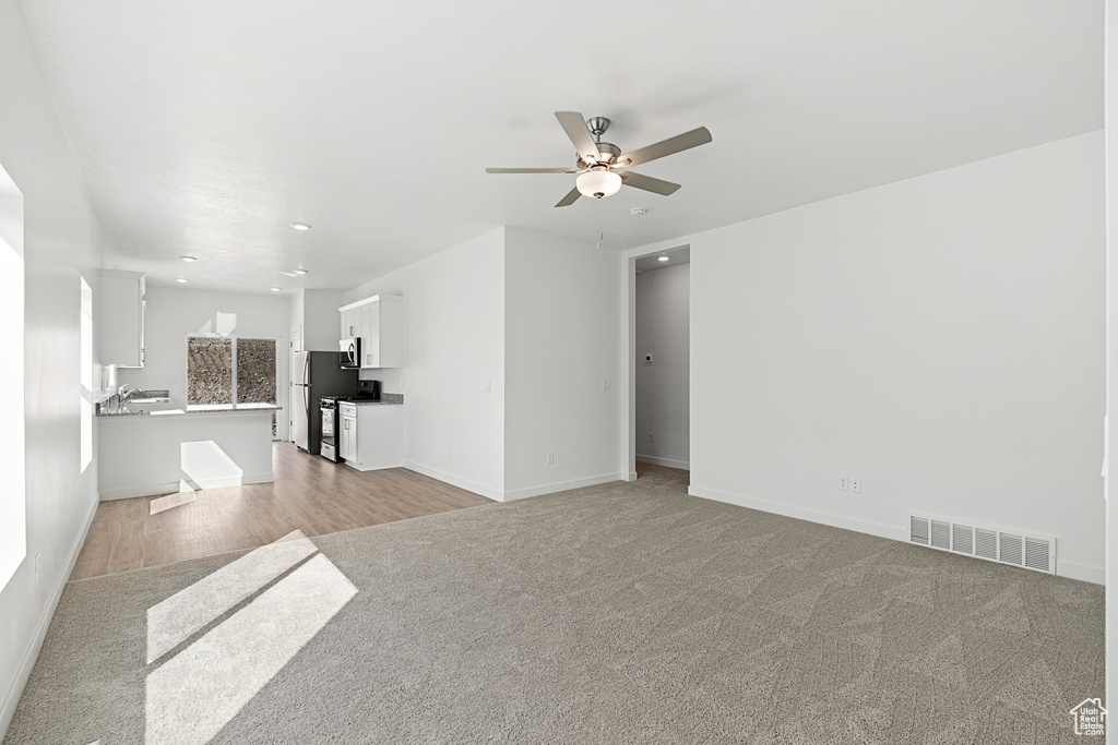 Unfurnished living room featuring light colored carpet and ceiling fan