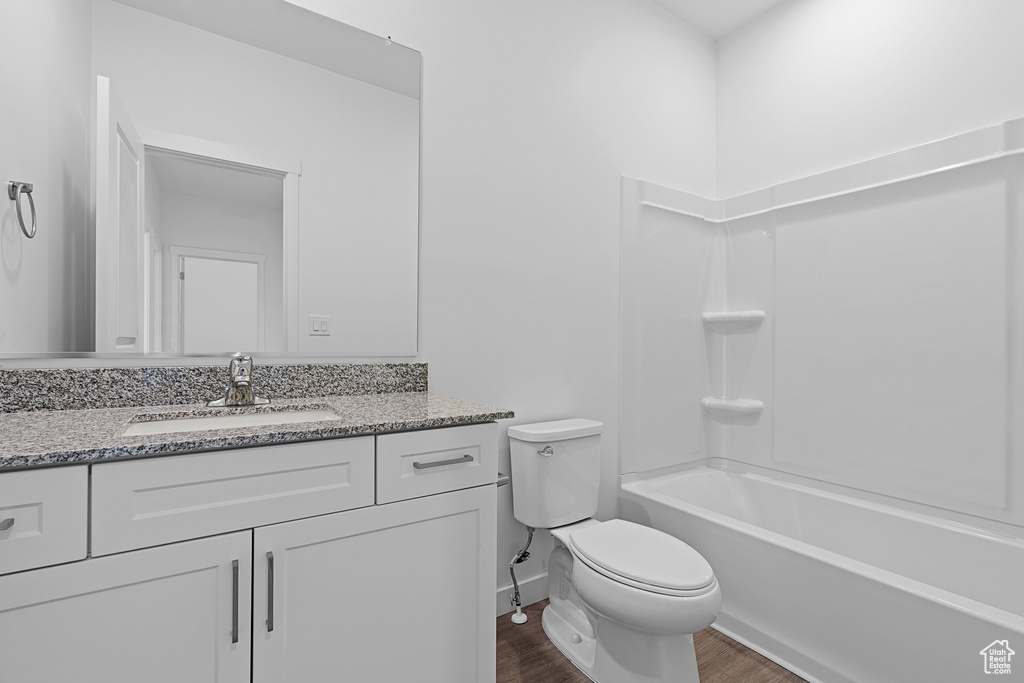 Full bathroom with oversized vanity, tub / shower combination, hardwood / wood-style flooring, and toilet
