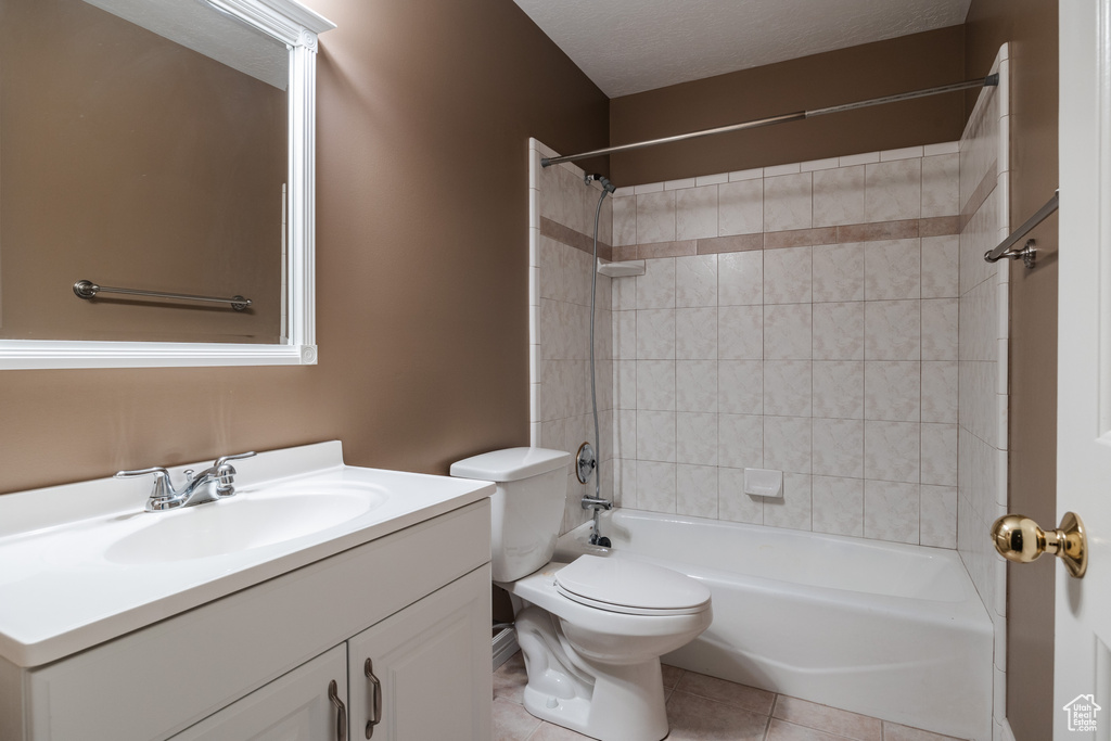 Full bathroom featuring vanity with extensive cabinet space, toilet, tiled shower / bath combo, a textured ceiling, and tile floors