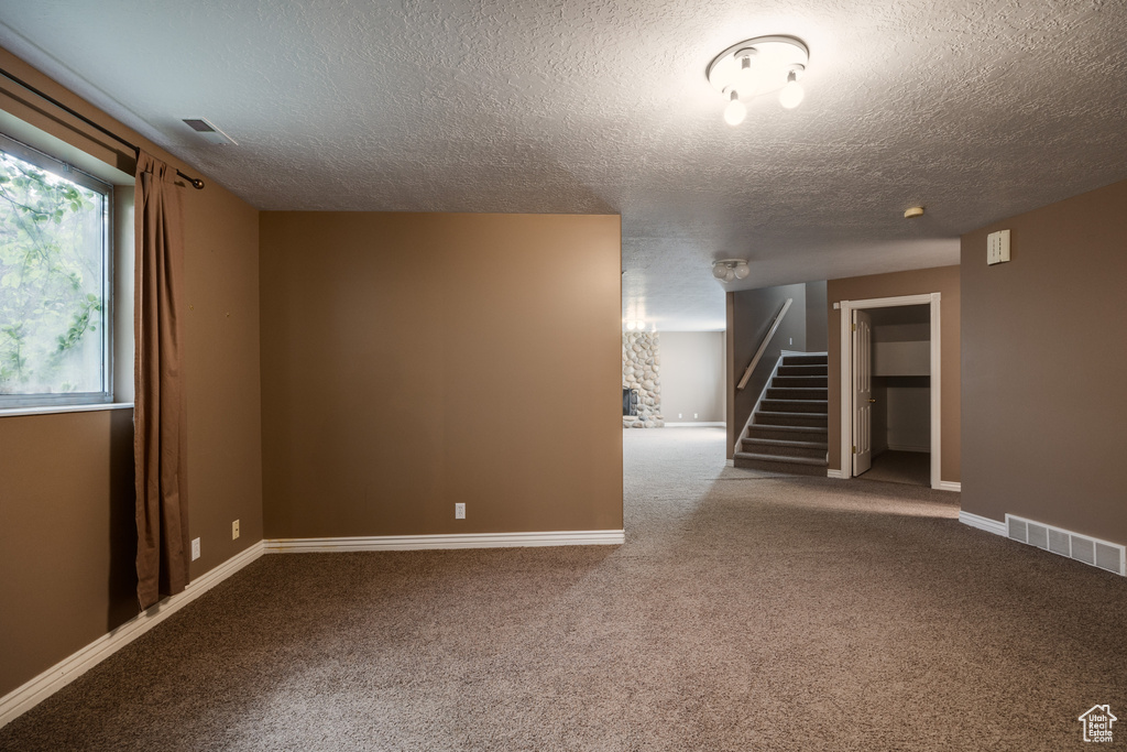 Empty room with carpet floors and a textured ceiling