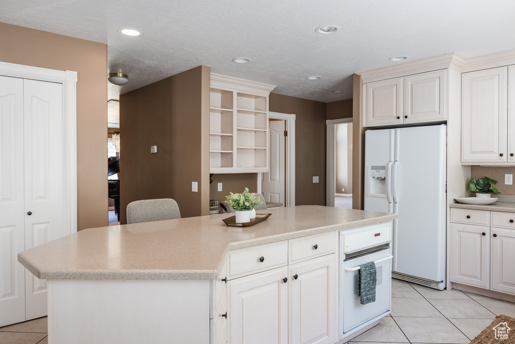 Kitchen with white appliances, light tile floors, and a kitchen island