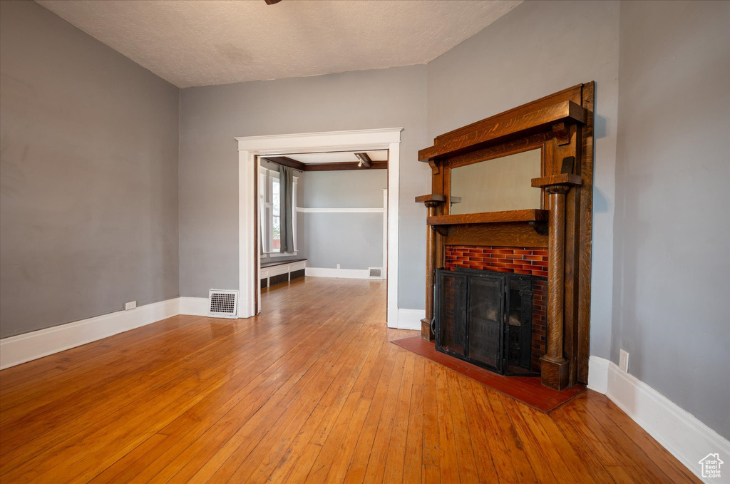 Unfurnished living room with hardwood / wood-style floors and a brick fireplace