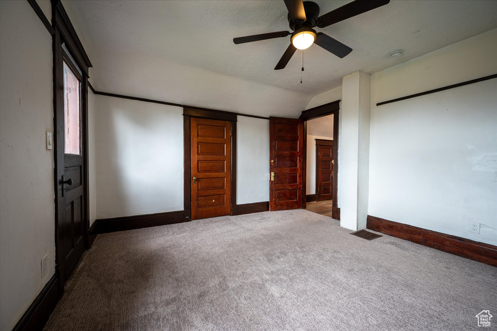 Unfurnished bedroom featuring dark carpet, ceiling fan, and lofted ceiling